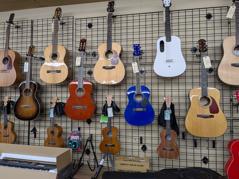 Acoustic guitars on wall including Fender and Lava travel guitar, plus ukuleles and a Casio keyboard