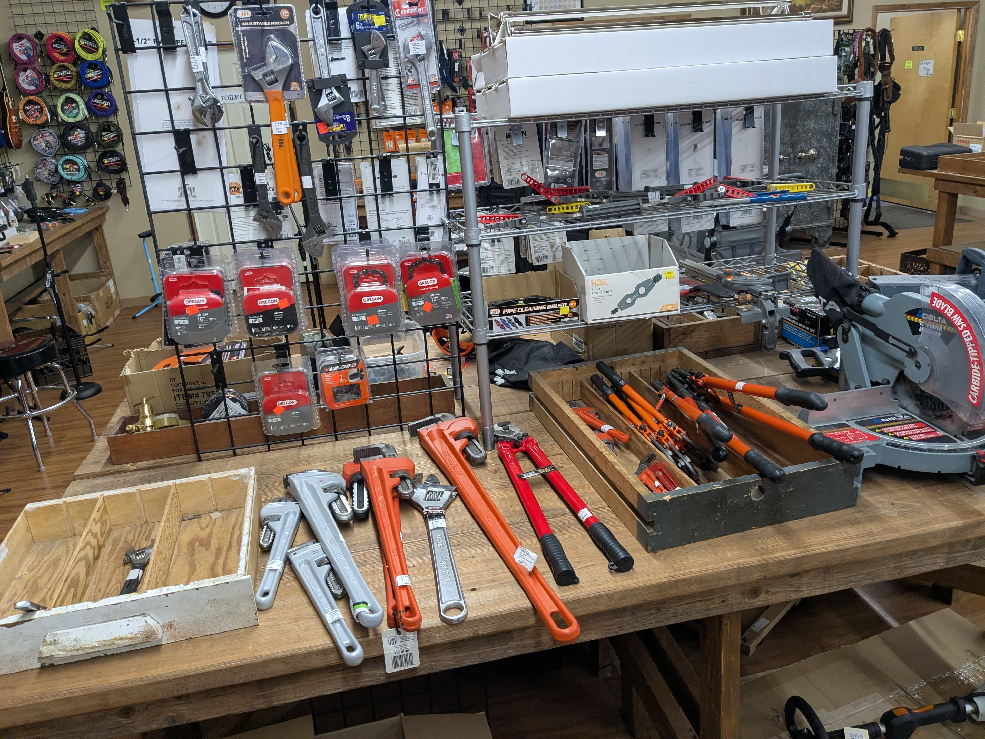Tools including pipe wrenches, chainsaw chains, bolt cutters, and a miter saw
