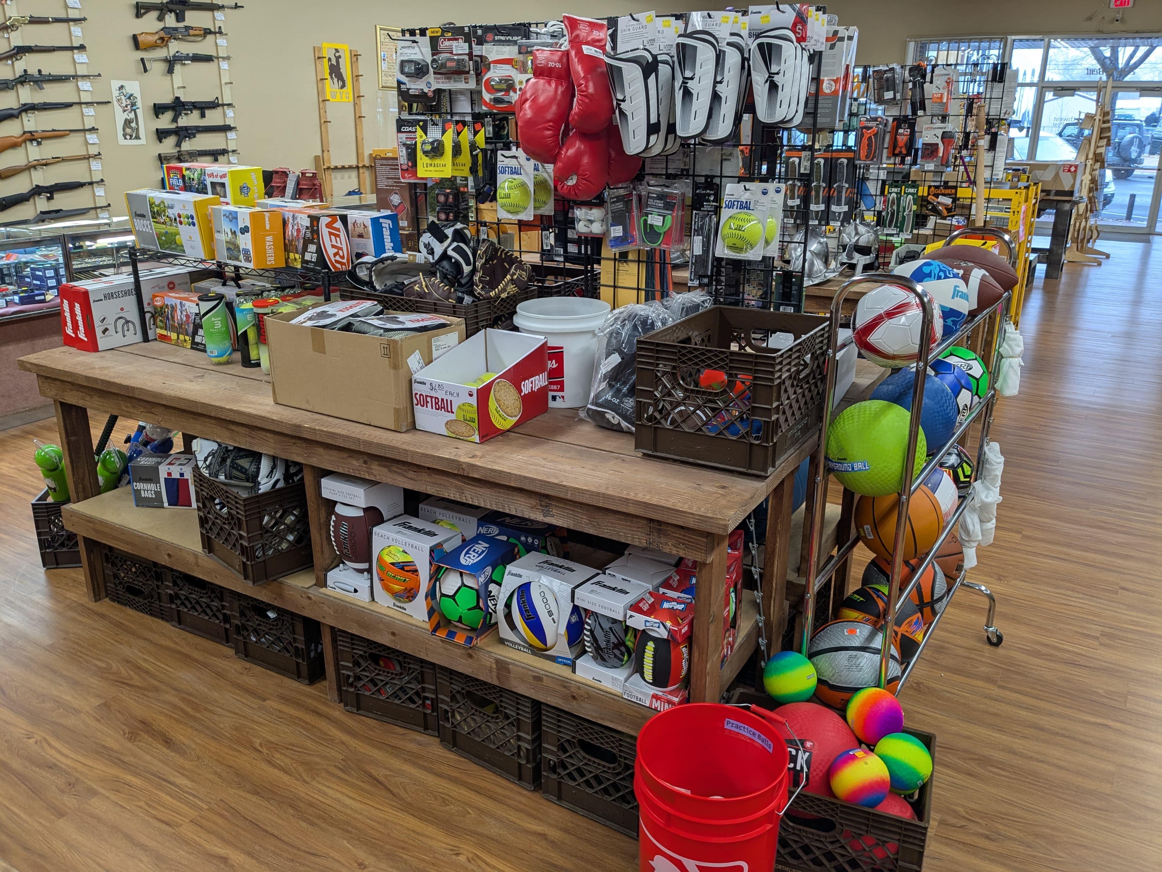 Sporting goods display with soccer balls, footballs, basketballs, boxing gloves, and Nerf products