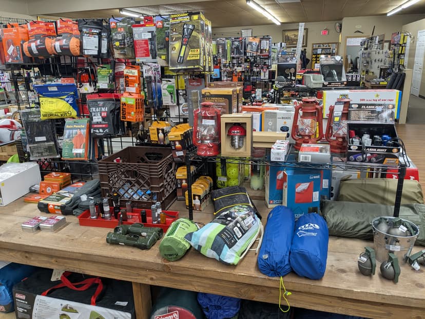 Camping and survival gear including flashlights, lanterns, sleeping bags, thermal blankets, first aid kit, and Coleman tent