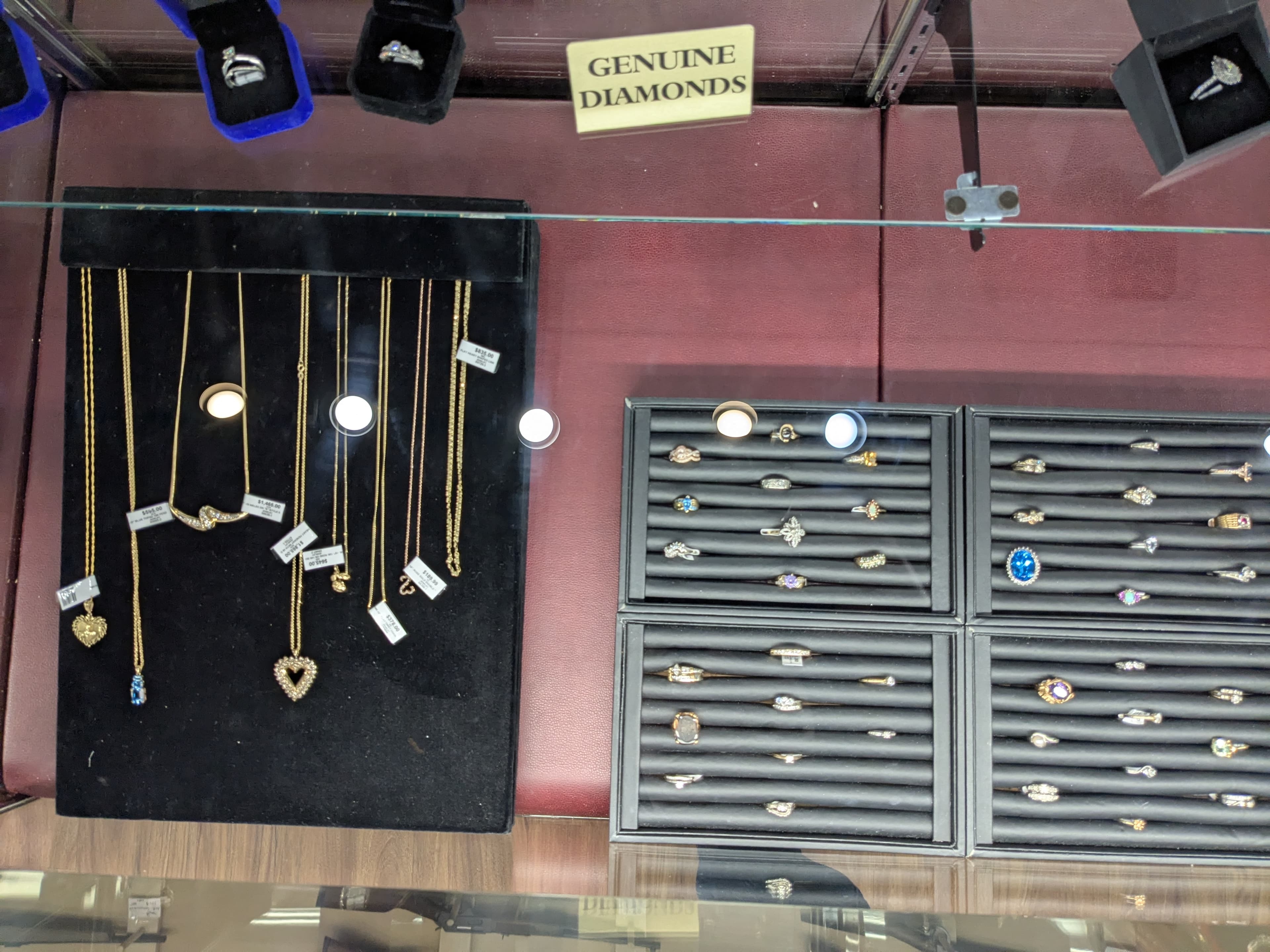 Jewelry display with gold necklaces with pendants, diamond rings, and gemstone rings