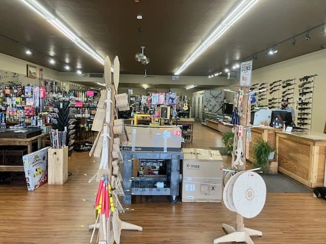 Store interior from the front entrance with ski displays, merchandise tables, and firearms wall in the background